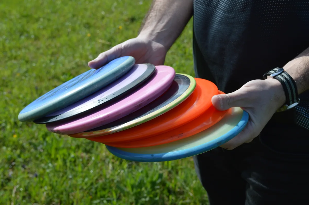 Zwei Hände halten viele, farbige Frisbees.